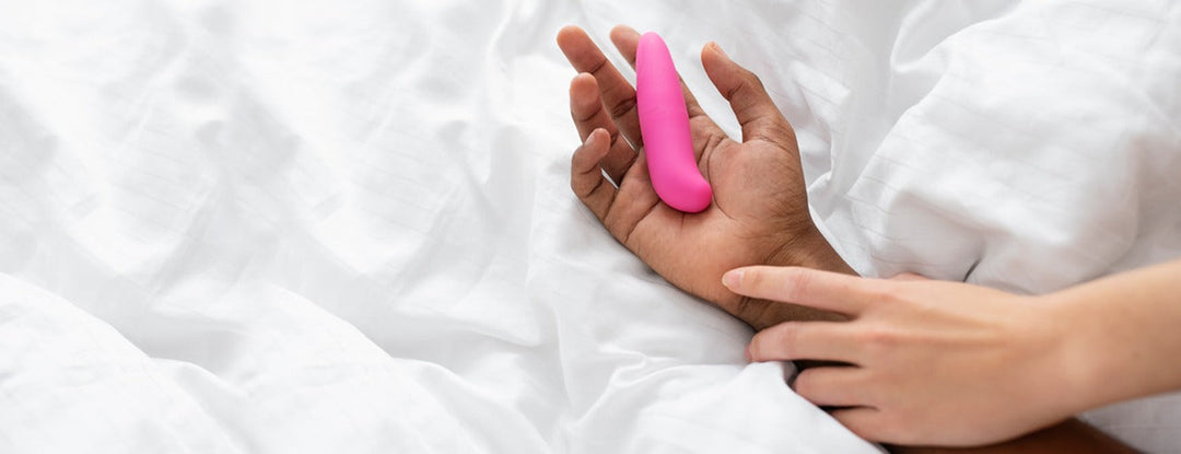 Pink silicone vibrator in hand, smooth curved design, body-safe material.