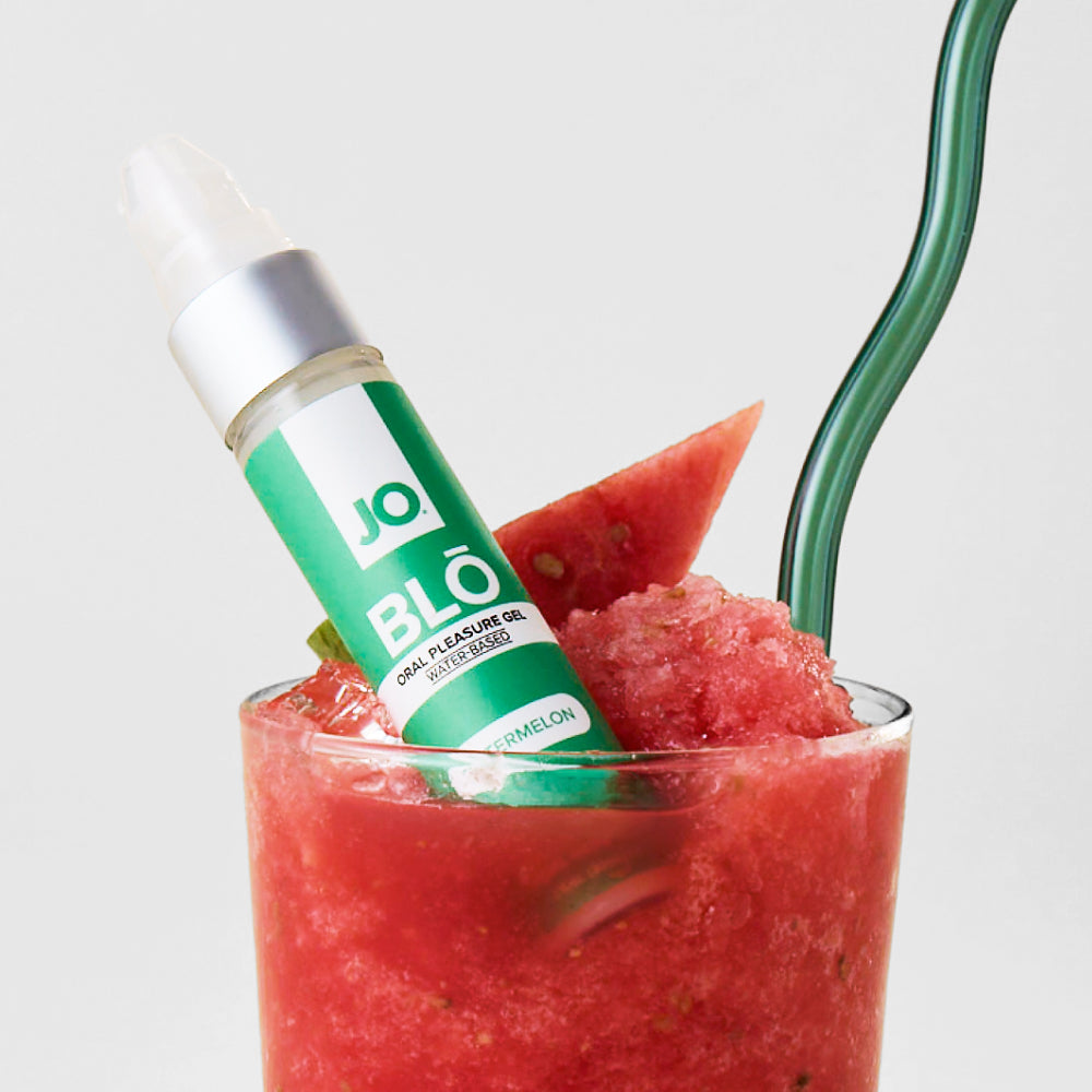 BLO Watermelon bottle propped in a glass of watermelon slush with a green straw