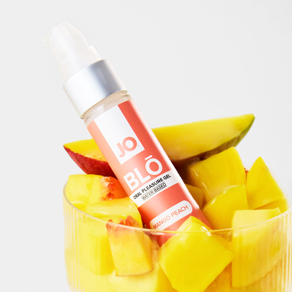BLO Mango Peach bottle propped in a glass of diced mango and peach