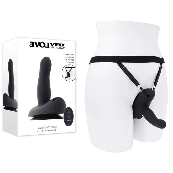 Evolved Come Closer retail box beside the Black strap-on harness fitted to a white mannequin hip