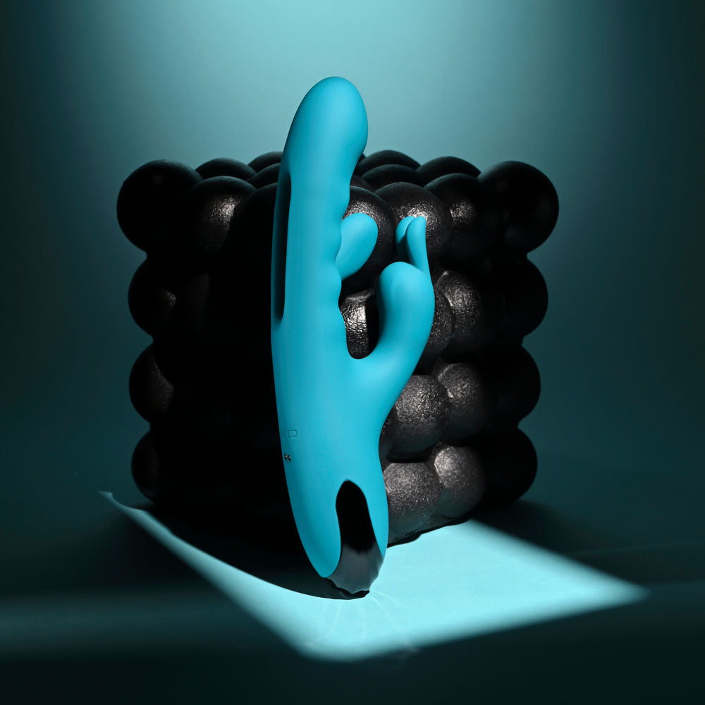 Evolved Bunny Tapper in Teal standing upright against a wall of glossy black spheres