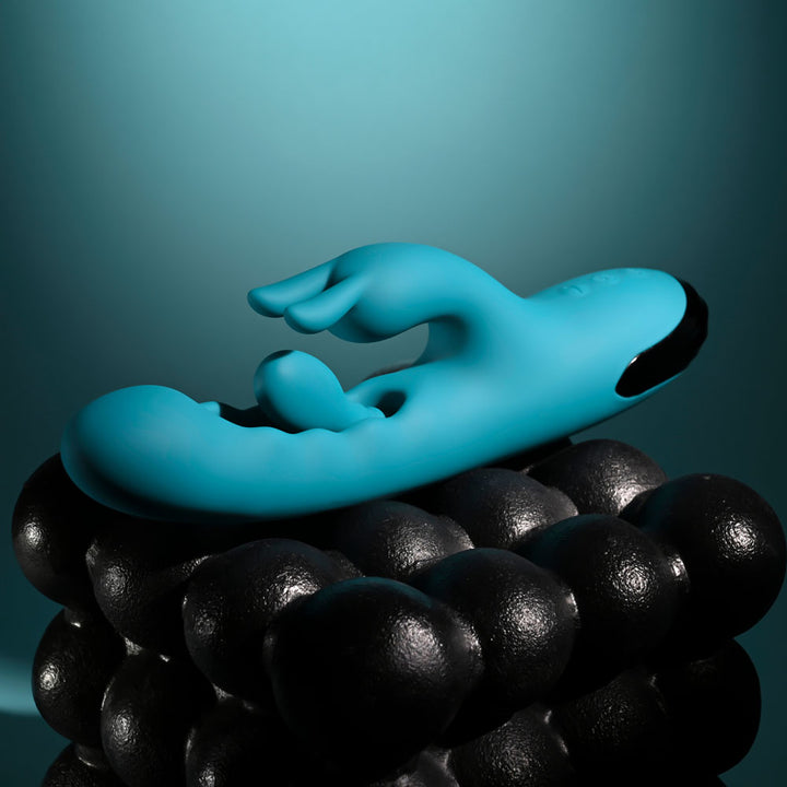 Evolved Bunny Tapper in Teal laid across black spheres from the opposite side, base at right