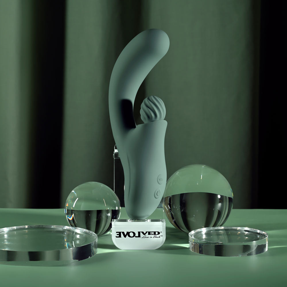 Evolved Spiral Charm in sage green standing on a clear Evolved base stand