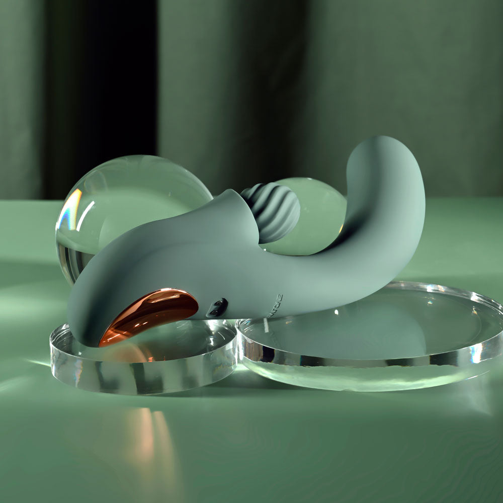 Evolved Spiral Charm in sage green lying flat at an angle, glass sphere behind it