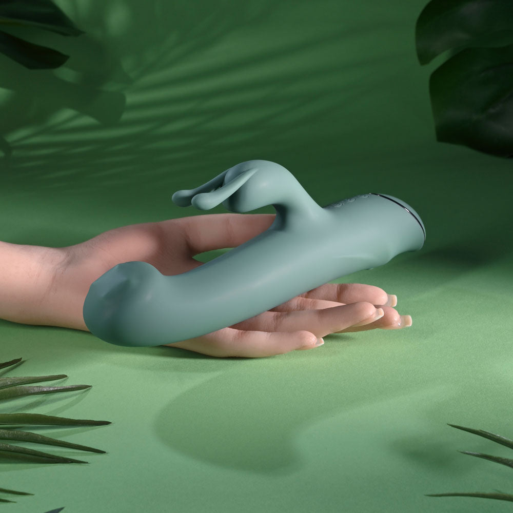 Evolved Satin Swirl in sage green lying across an open hand, green backdrop
