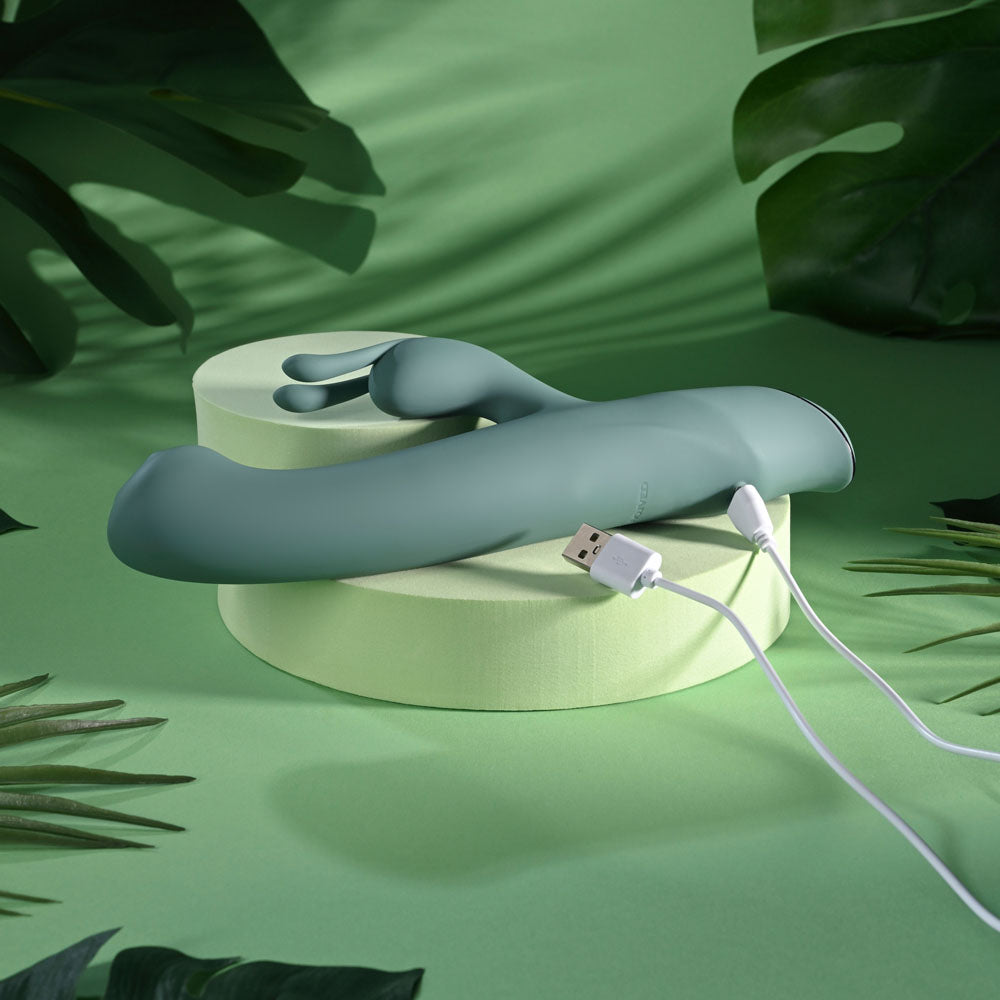Evolved Satin Swirl in sage green on a podium with its white USB charging cable attached