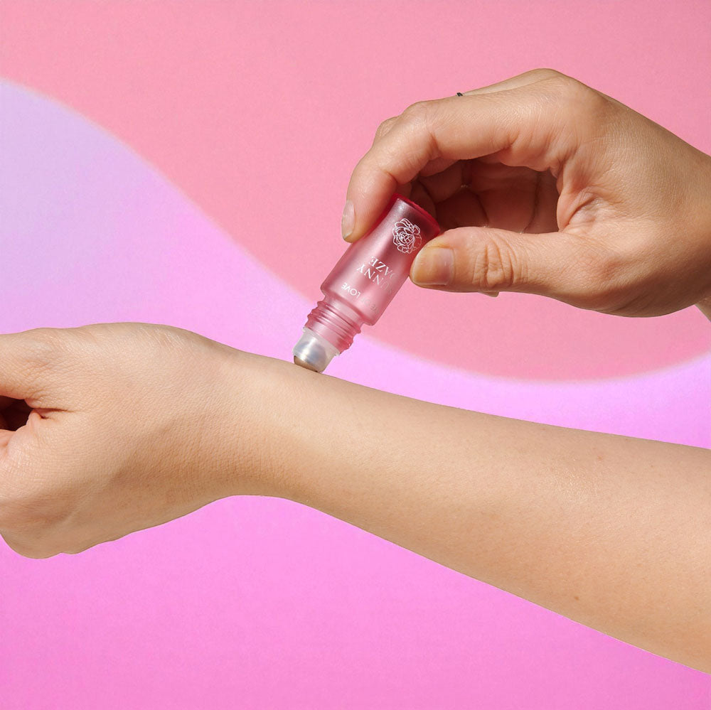 Pink Sunny Daze roll-on being applied to a wrist against a pink background