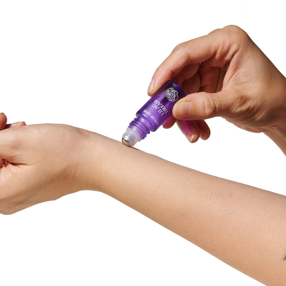 Close-up of the Lilac Dream roll-on ball being rolled onto a wrist, white background