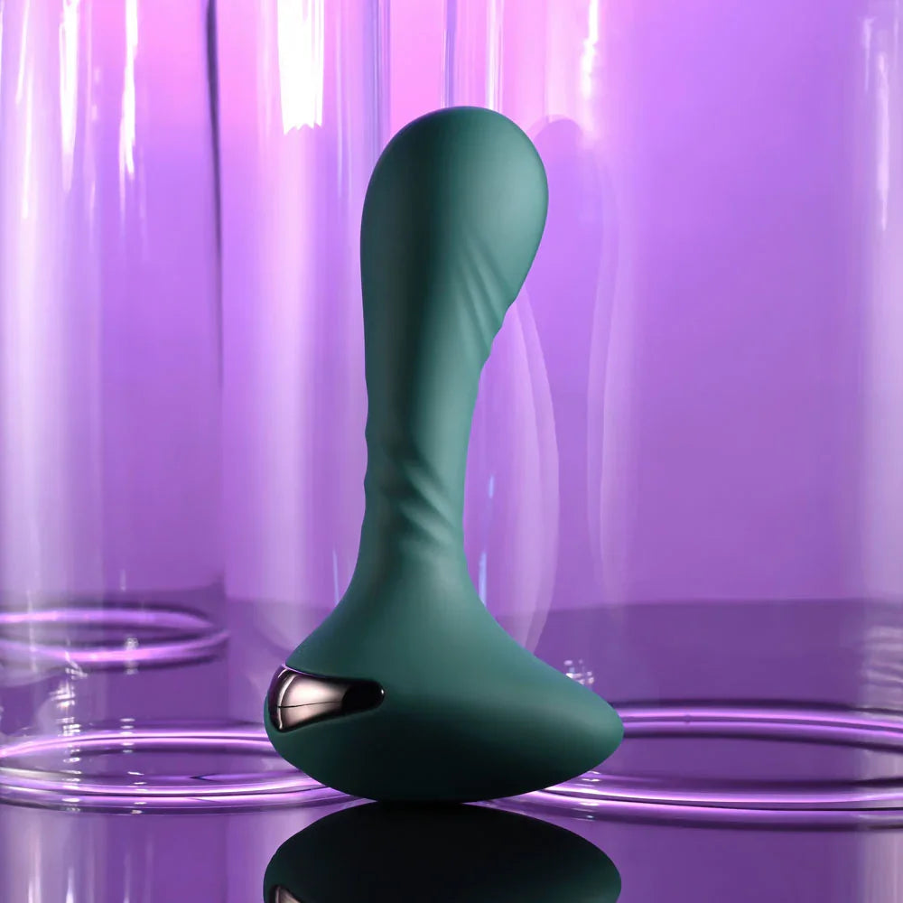 Gender X Goes Anywhere vibrator in Green standing at three-quarters, purple glass behind