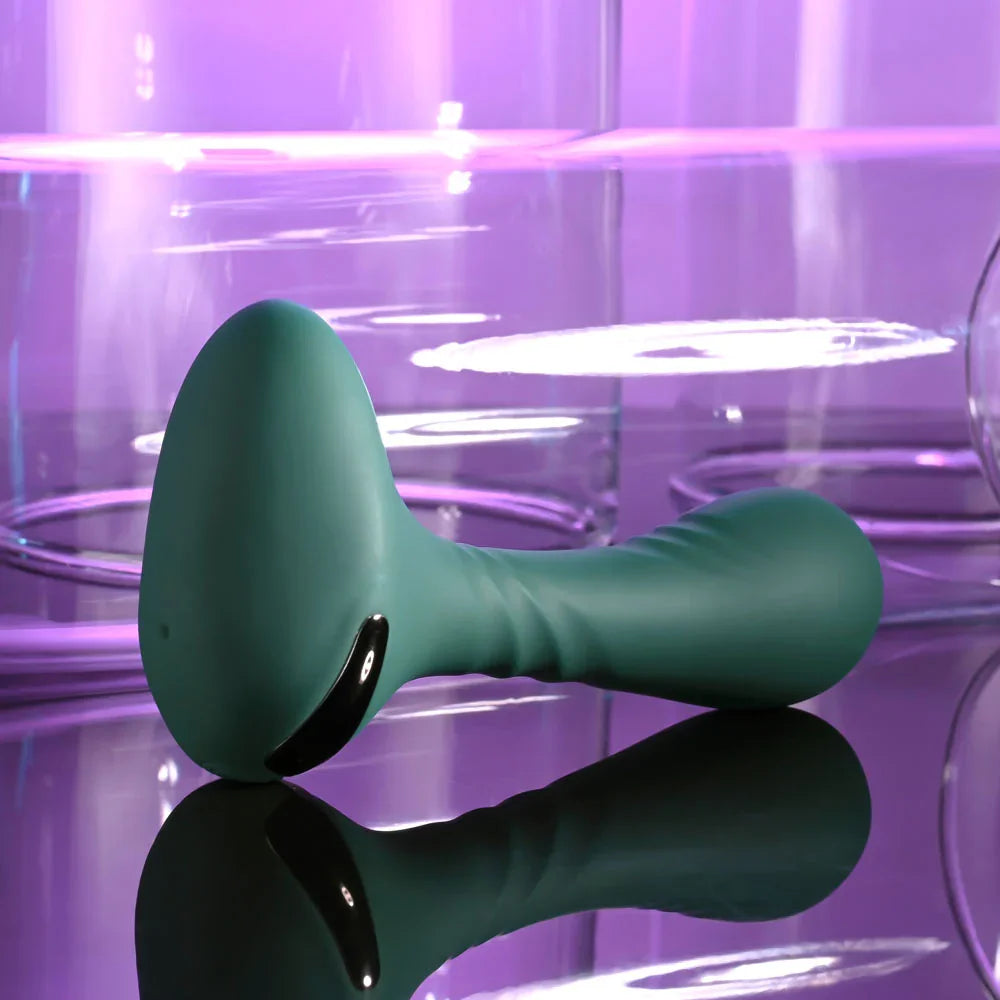 Gender X Goes Anywhere vibrator in Green seen from the flared base end, lying down