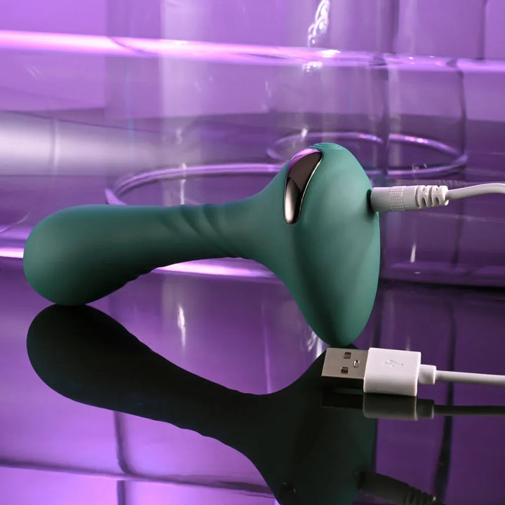 Gender X Goes Anywhere vibrator in Green with its magnetic USB charging cable attached
