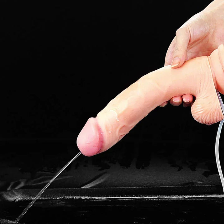 Hands holding the Cumming Softee 9 inch dong sideways as it squirts a stream of liquid