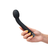 A hand with orange-painted nails holds a Maia PRESTON - Black 17.8 cm USB Rechargeable G-Spot Vibrator, featuring a bulbous tip and metallic ring. Its sleek silicone coating on a plain white background enhances its modern allure.