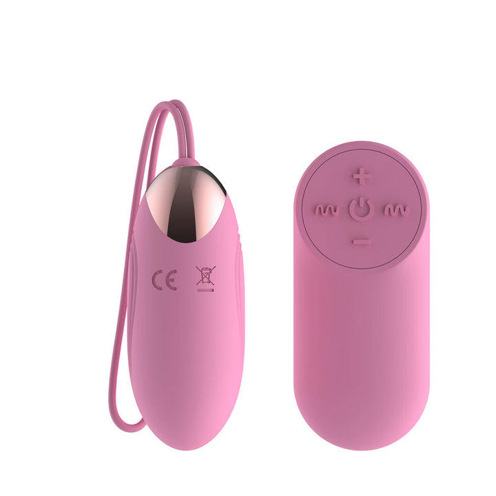 Passion Play Vibrating Egg in Pink upright, rose gold cap uppermost, remote alongside