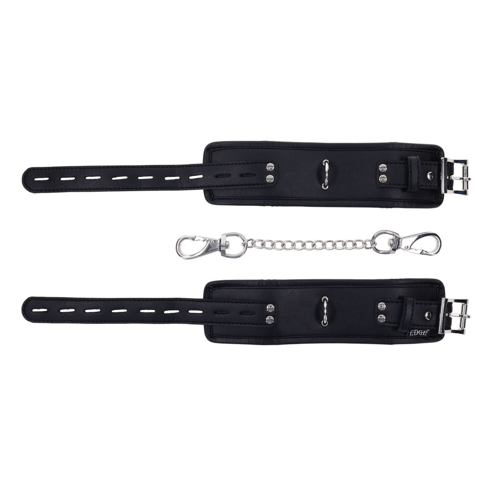 EDGE Handcuffs - Black Restraints boast black leather wrist cuffs with precise stitching and silver buckles. A detachable metal chain fastens to small loops, providing secure restraint. Adjustable buckles ensure a perfect fit, all showcased elegantly against a white background.