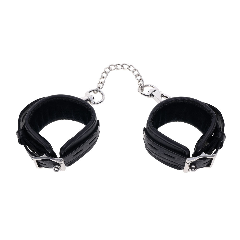 The EDGE Handcuffs - Black Restraints feature adjustable black leather cuffs connected by a short silver chain. Complete with silver metal details, the minimalist design offers comfort with inside padding, ensuring practicality meets style.