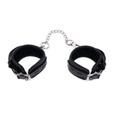 The EDGE Handcuffs - Black Restraints feature adjustable black leather cuffs connected by a short silver chain. Complete with silver metal details, the minimalist design offers comfort with inside padding, ensuring practicality meets style.