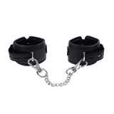 The EDGE Handcuffs - Black Restraints feature a sleek black leather design, a silver metal chain with clips, and adjustable buckle closures for secure restraint. The smooth leather and shiny metal enhance their allure.