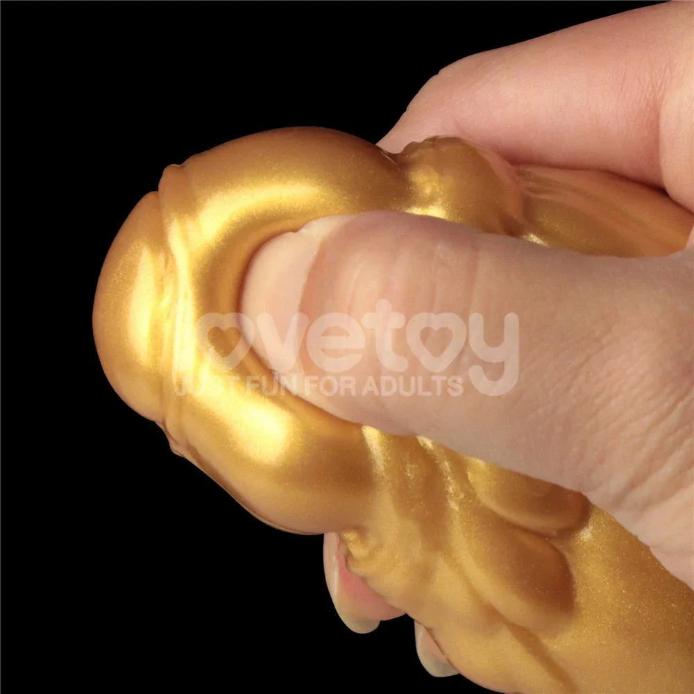 Hand squeezing the gold shaft of the Aerosx dildo to show the soft dual density outer layer
