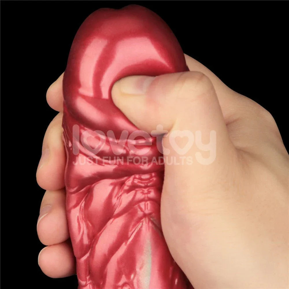 Hand squeezing the red inflated head of the Aerosx 8 inch dildo to show the soft silicone skin
