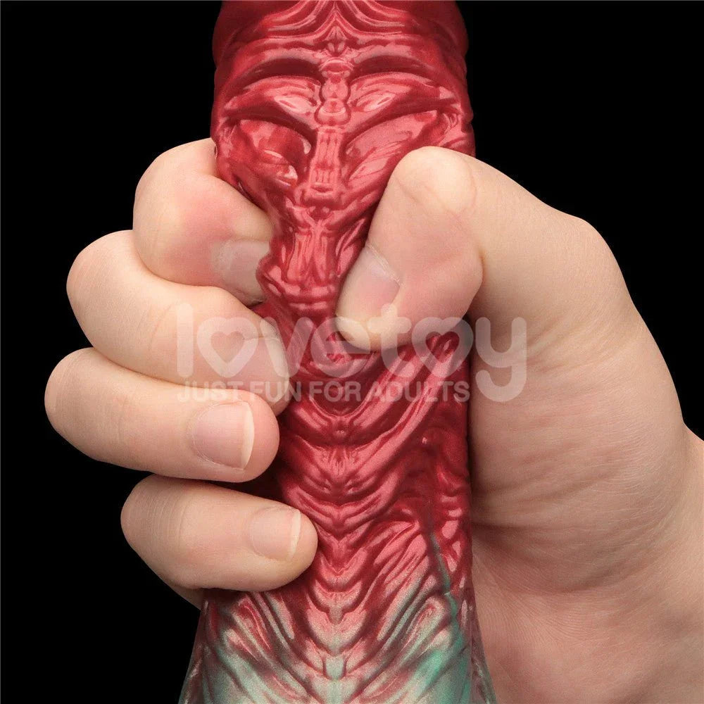 Fist wrapped around the veined red shaft of the Aerosx 8 inch dildo for scale