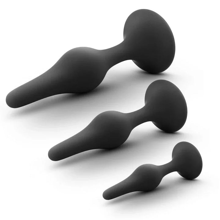 Three black beginner plugs lying in a diagonal row, smallest to largest