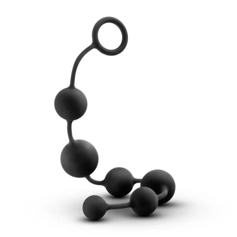 Large black silicone anal beads coiled with the pull ring standing upright