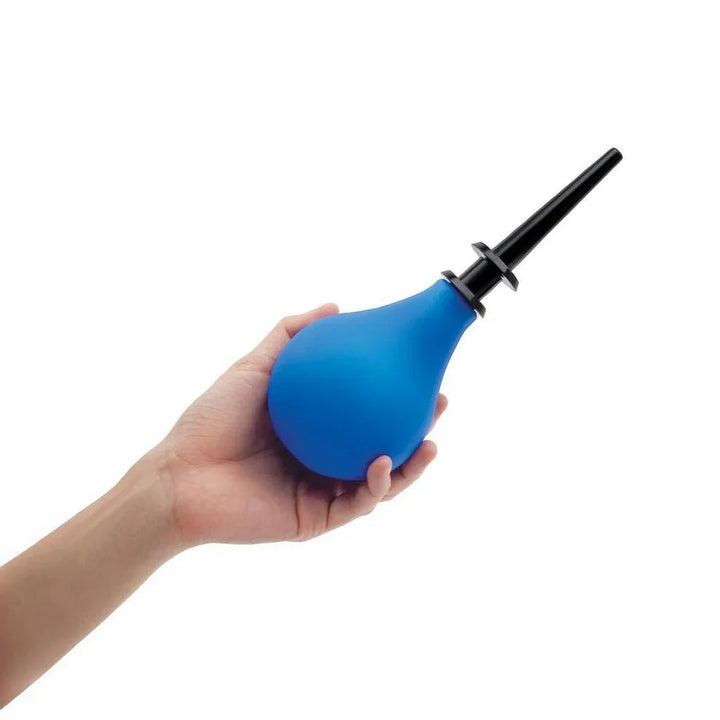 A hand squeezing the blue AquaClean douche bulb with the tapered nozzle attached