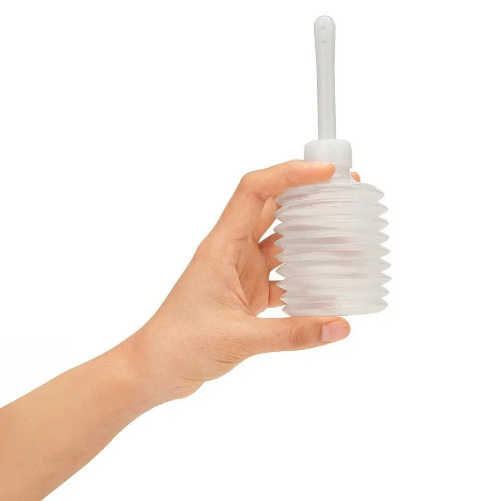 A hand holding the clear concertina travel douche supplied with the Ergo set