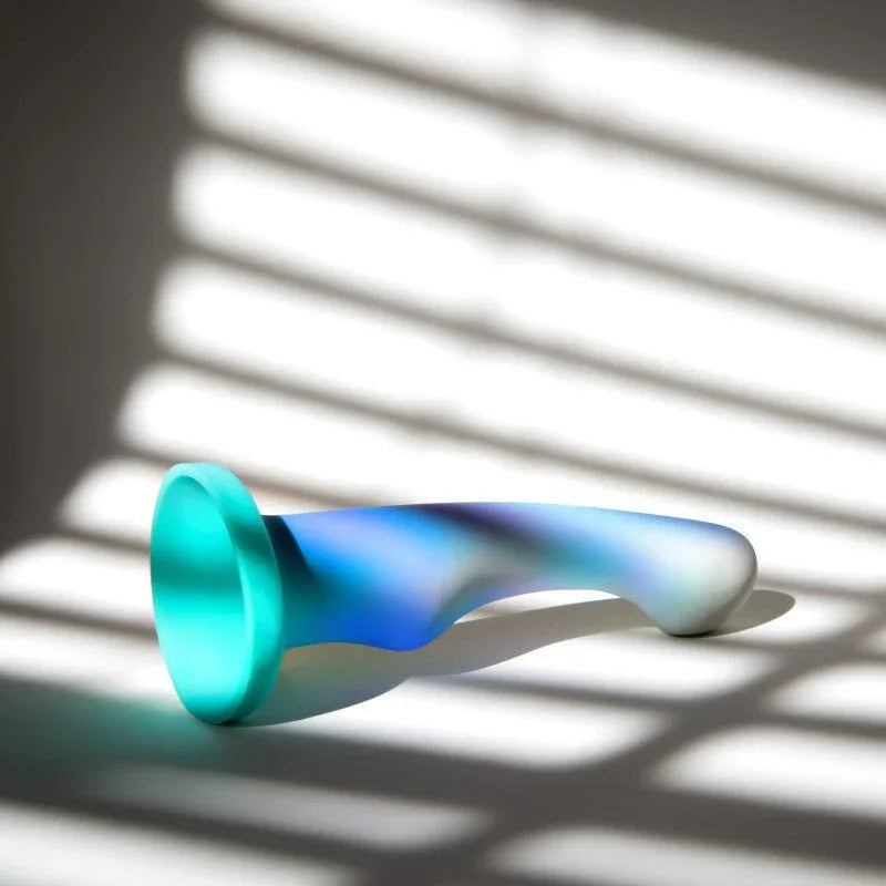 Opal Dreams dildo lying in striped window-blind shadows, aqua suction base forward