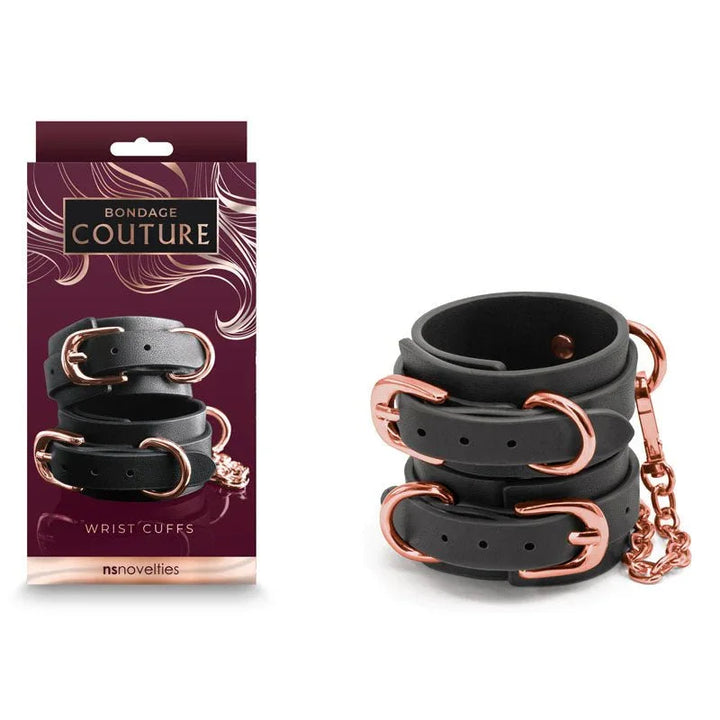 Bondage Couture wrist cuffs in Black with rose gold buckles, beside the burgundy box