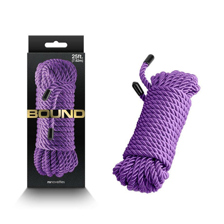 The image features a packaged Bound Rope - Purple with a loose coil of non-chafing polyester fibre rope. The packaging has a transparent window with BOUND in gold lettering, and the 25-foot (7.6-meter) neatly coiled rope has black plastic-capped ends.