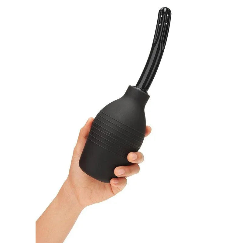 A hand squeezing the black CleanScene douche bulb, ribbed soft nozzle angled upward