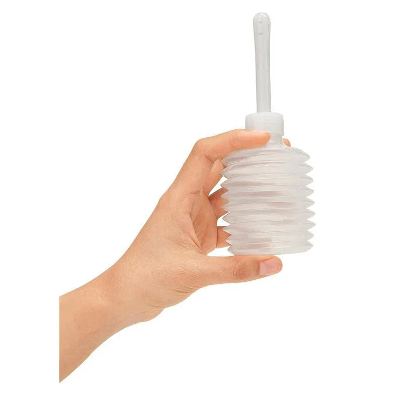 A hand holding the clear concertina travel douche included with the CleanScene set