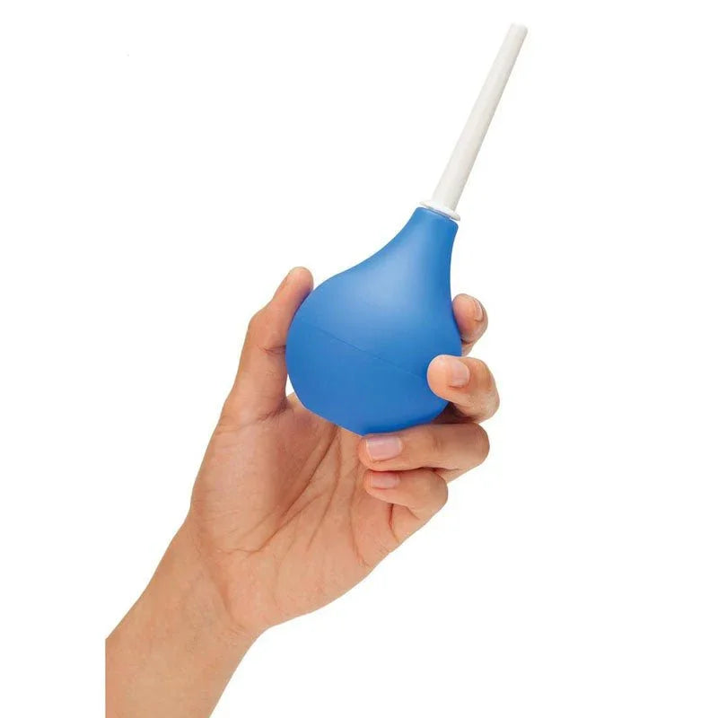A hand squeezing the blue CleanScene travel bulb, white nozzle pointing up