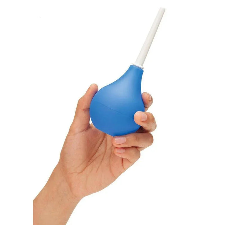 A hand squeezing the blue CleanScene travel bulb, white nozzle pointing up