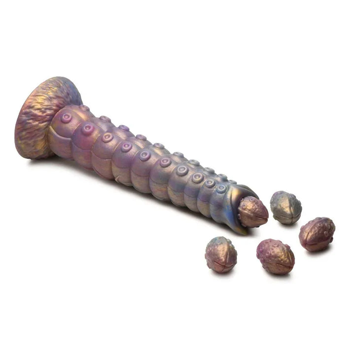 Deep Invader dildo lying flat on white with its soft eggs spilling from the tip