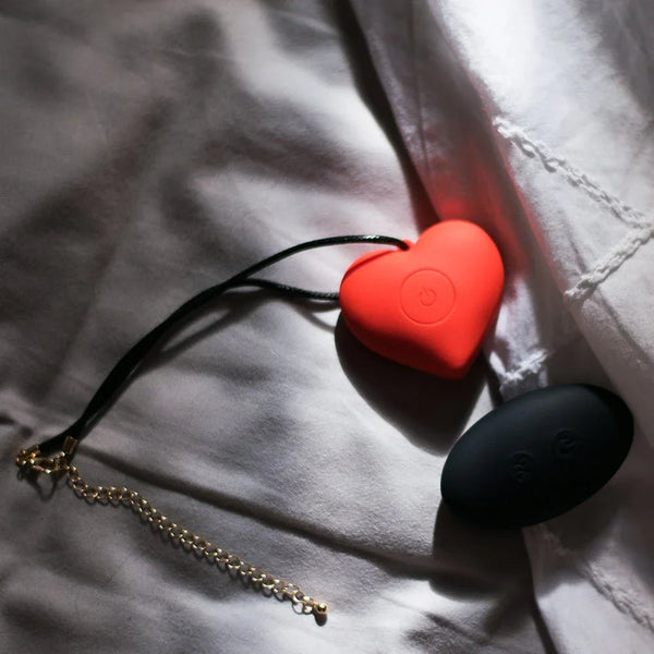 ELIXIR Play Aphrodite red heart vibe with cord necklace and black remote on bedding