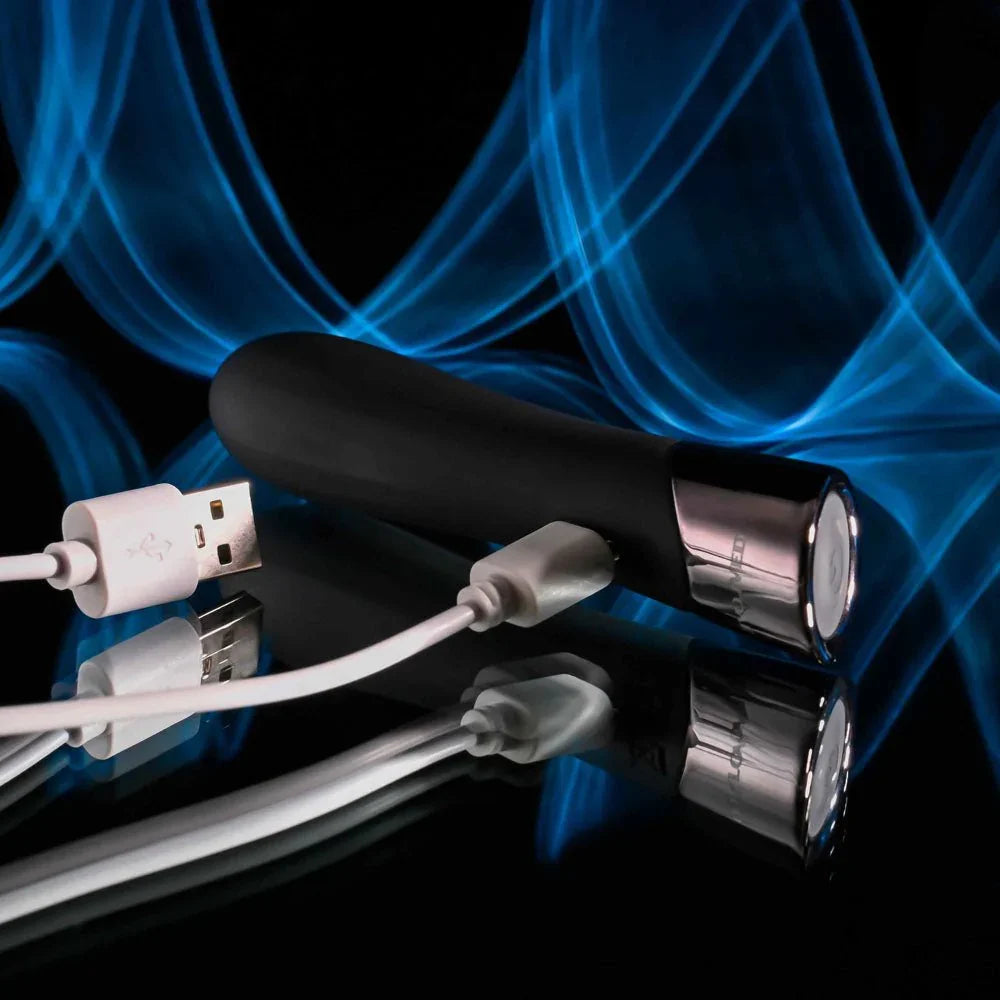 Evolved Back In Black bullet in Black with its white USB charging cable plugged into the base