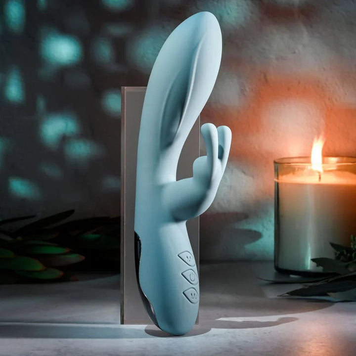 Evolved Boss Bunny in Baby Blue upright against a stand, lit candle and teal bokeh behind