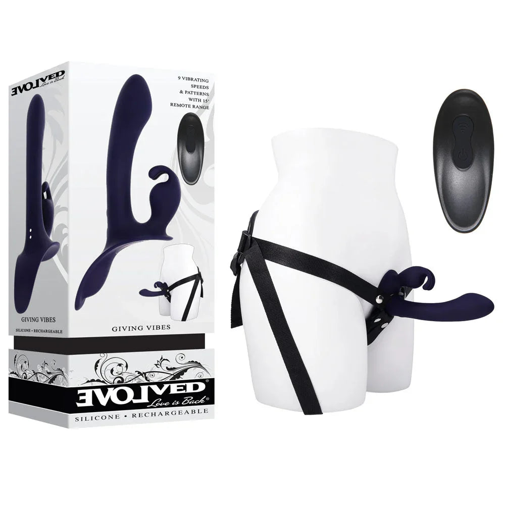 Evolved Giving Vibes retail box beside the navy strap-on harness on a white mannequin hip, remote alongside