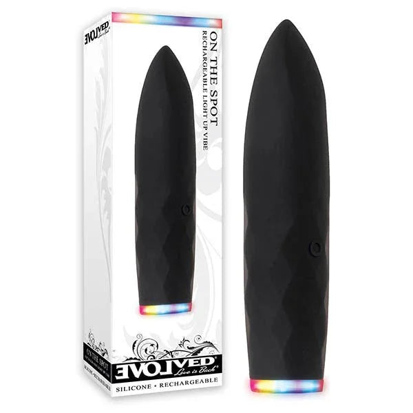 Evolved On The Spot retail box beside the Black bullet vibrator, rainbow LED band lit at its base
