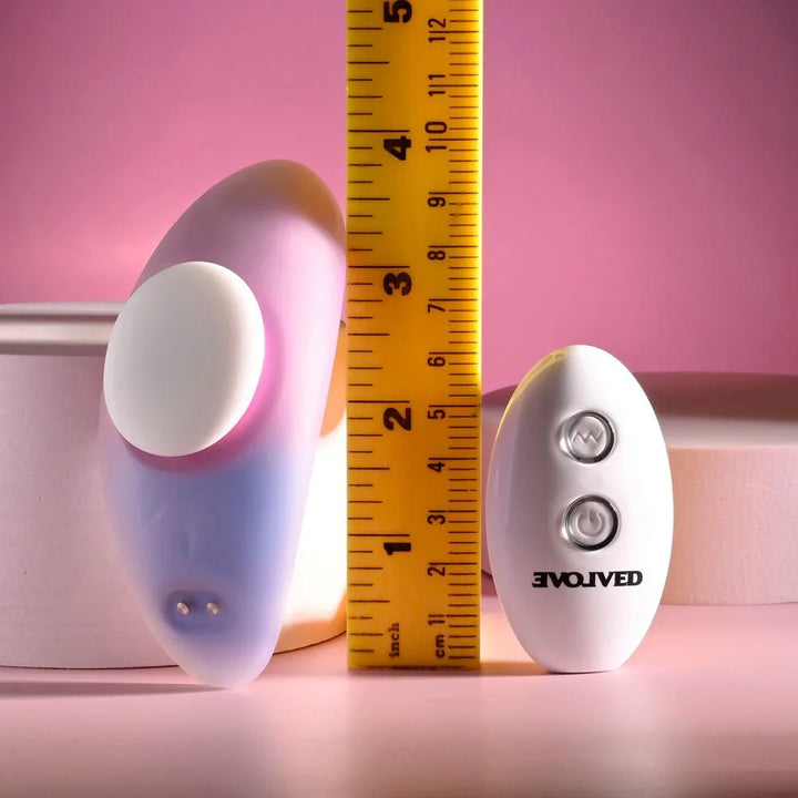 Evolved Paradise Panty in Pink/Purple beside a tape measure, reading about 3 inches, remote behind