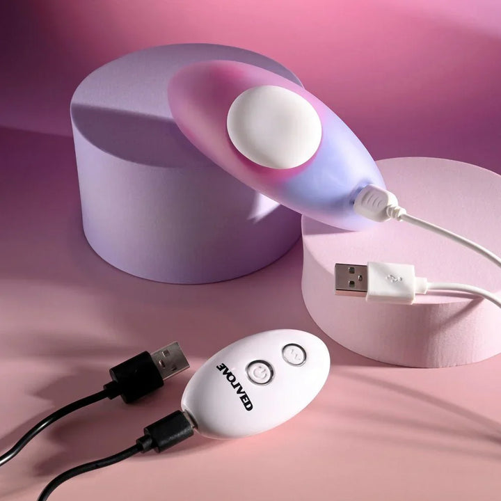 Evolved Paradise Panty in Pink/Purple on a podium with its USB charging cable attached, remote in front