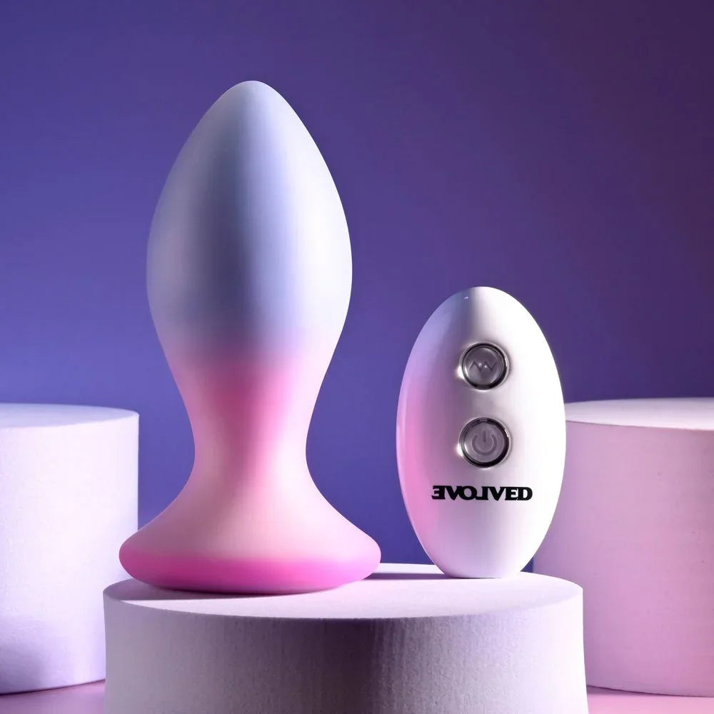 Evolved Paradise Plug in Pink/Purple upright on a podium, white two-button remote alongside