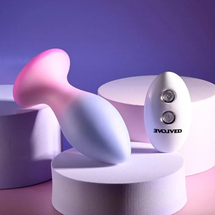 Evolved Paradise Plug in Pink/Purple lying on its side, base up and to the left, remote at right