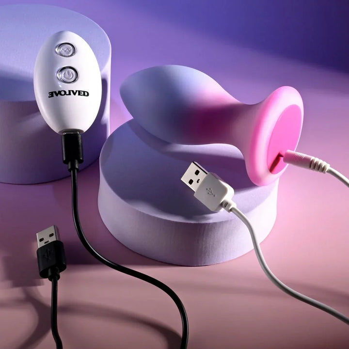 Evolved Paradise Plug in Pink/Purple on its side with the charging cable clipped to its base
