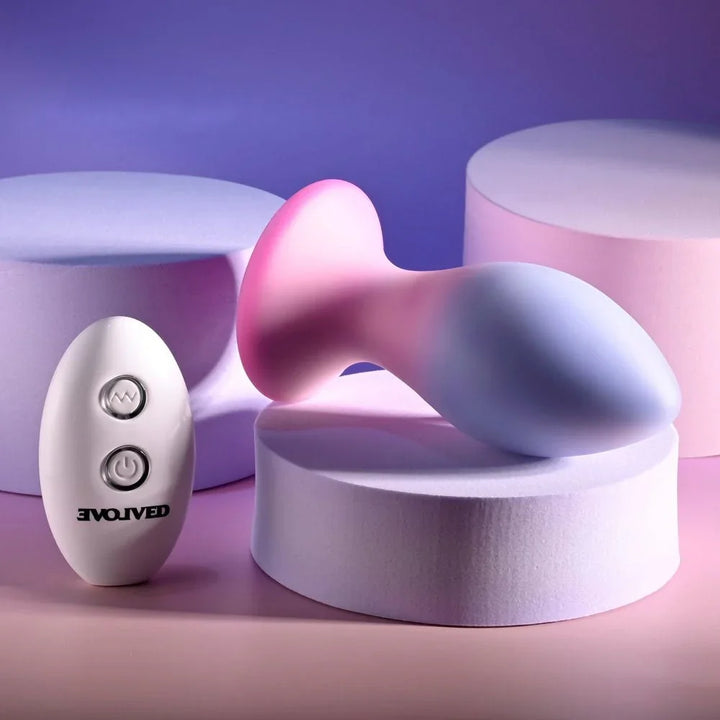 Evolved Paradise Plug in Pink/Purple lying on its side, base to the left, remote behind
