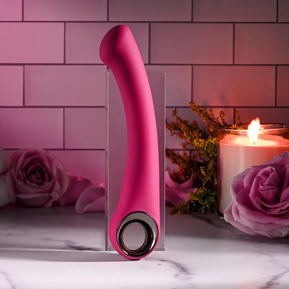 Evolved Pleasure Curve in Pink upright, close on the chrome ring in the handle, candle at right