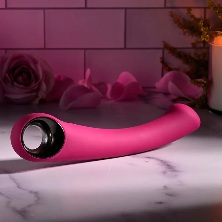 Evolved Pleasure Curve in Pink lying flat with the chrome ring handle to the left